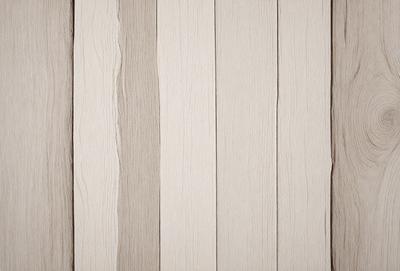 The primary subject of the image is a wooden wall with a striped pattern. The setting is a room with a wooden floor. The visual style is a photo of a wooden wall. The dominant colors are white and brown, giving the wall a natural and warm appearance.