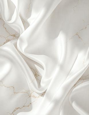 The primary subject of the image is a white sheet of fabric, possibly a tablecloth or a curtain. The fabric is draped over a marble surface, which serves as the setting or background. The visual style of the image is a close-up of the fabric, showcasing its texture and details. The colors in the image are predominantly white, giving it a clean and elegant appearance. The overall mood of the image is sophisticated and elegant, with the white fabric and marble surface creating a