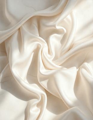 The primary subject of the image is a white sheet of fabric, which is the main object, scene, or focus of the image. The setting is a white background, which provides a clean and minimalistic environment. The visual style is a photo, capturing the fabric's texture and details. The colors and mood of the image are predominantly white, creating a sense of simplicity and purity.