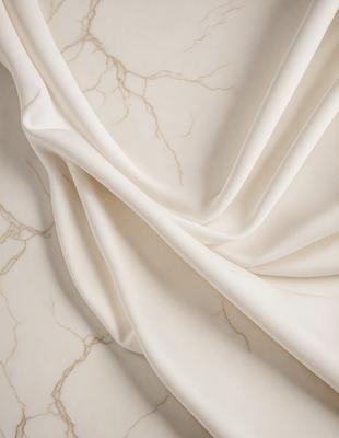 The primary subject of the image is a white fabric, possibly a sheet or a curtain, with a marble-like texture. The setting is a white background, which provides a clean and minimalist appearance. The visual style is a close-up of the fabric, showcasing its texture and details. The colors and mood of the image are predominantly white, giving it a clean and elegant feel.