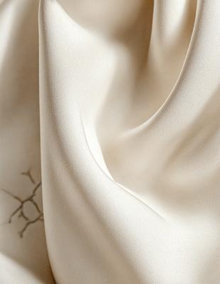 The primary subject of the image is a white sheet of fabric. The setting is a room with a white background. The visual style is a close-up of the fabric, showcasing its texture and details. The colors and mood of the image are predominantly white, giving it a clean and minimalist appearance.