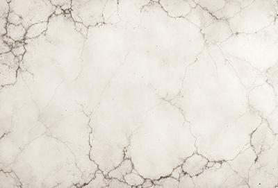 The primary subject of the image is a white marble wall with a rough texture. The setting is a room with a white marble floor. The visual style is a photo of the marble wall. The colors and mood of the image are predominantly white, giving it a clean and elegant appearance.