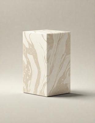 The primary subject of the image is a square white box with a marbled texture. The box is placed on a grey surface, which serves as the setting or background. The visual style of the image is a close-up of the box, showcasing its unique texture and design. The colors and mood of the image are predominantly neutral, with the white box and grey surface creating a calm and minimalist atmosphere.