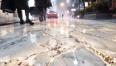 The primary subject of the image is a marble floor with a pattern of gold streaks. The setting is a city street at night, with a car driving down the road and a few people walking nearby. The visual style is a photo, and the colors and mood are a combination of gold, black, and white, creating a luxurious and elegant atmosphere.