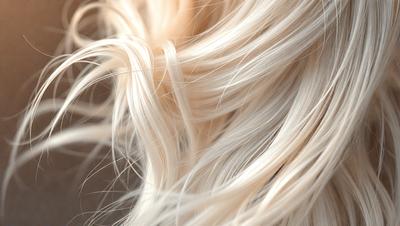 The primary subject of the image is a blonde woman with long, curly hair. The setting is a close-up of her hair, and the visual style is a photo. The colors in the image are predominantly blonde and white, giving the scene a warm and natural atmosphere.
