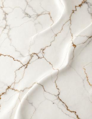 The primary subject of the image is a marble countertop with a white and gold color scheme. The setting is a kitchen or bathroom, as the countertop is a part of a counter. The visual style is a close-up of the marble countertop, showcasing its intricate patterns and textures. The colors and mood of the image are elegant and sophisticated, with the white marble providing a clean and timeless appearance, while the gold accents add a touch of luxury and warmth.