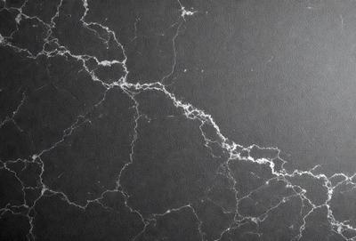 The primary subject of the image is a marble wall with a black background. The setting is a room with a black countertop. The visual style is a photo of a marble wall, and the colors and mood are dark and moody.