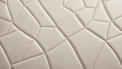 The primary subject of the image is a white tile with a pattern of irregular shapes. The setting is a wall, and the visual style appears to be a photo. The dominant colors are white and gray, creating a clean and minimalist atmosphere.