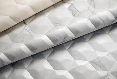 The primary subject of the image is a patterned fabric, featuring a combination of white and grey colors. The setting is a table, and the visual style appears to be a photo. The fabric has a unique design, giving it a modern and sophisticated appearance. The overall atmosphere of the image is elegant and stylish.