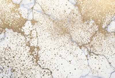 The primary subject of the image is a marble countertop with a gold-colored, speckled pattern. The setting is a kitchen or bathroom, as the countertop is a part of a counter. The visual style is a close-up of the marble countertop, showcasing its unique and elegant design. The colors and mood of the image are warm and inviting, with the gold speckles adding a touch of luxury and sophistication.