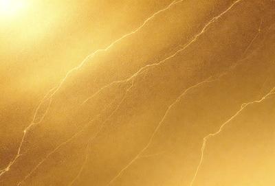 The primary subject of the image is a gold-colored wall with a pattern of light and dark streaks. The setting is a room with a gold-colored wall, and the visual style is a close-up of the wall. The colors and mood of the image are predominantly gold and warm, creating a sense of luxury and elegance.