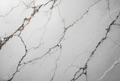 The primary subject of the image is a close-up of a marble wall with a cracked and textured surface. The setting is a room with a grey background. The visual style is a photo, and the colors and mood are predominantly grey and somewhat moody.