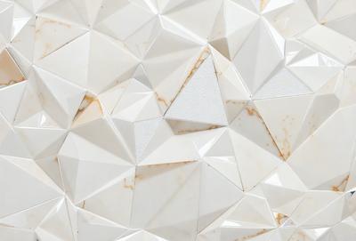 The primary subject of the image is a white marble wall with a pattern of triangles. The setting is a room with a white background, and the visual style is a close-up of the marble wall. The colors and mood of the image are predominantly white, giving it a clean and elegant appearance.