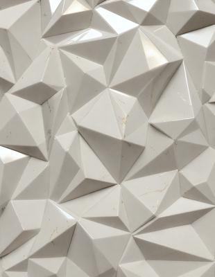The primary subject of the image is a white tile wall with a geometric pattern. The setting is a room with a white tile floor. The visual style is a close-up of the tile wall, showcasing the intricate design. The dominant colors are white and gray, creating a clean and modern atmosphere.