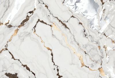The primary subject of the image is a marble countertop with a gold-colored vein running through it. The setting is a kitchen, and the visual style is a close-up of the marble countertop. The colors and mood of the image are predominantly neutral, with the gold vein adding a touch of warmth and sophistication to the marble surface.