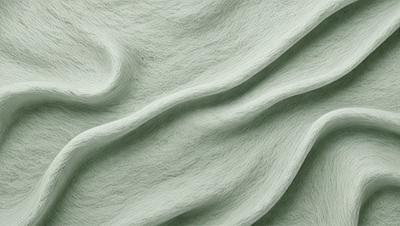 The primary subject of the image is a green fabric, which appears to be a piece of wool. The setting is a close-up view of the fabric, showcasing its texture and color. The visual style is a realistic representation of the fabric, with no indication of digital art or illustration. The colors and mood of the image are predominantly green, giving it a natural and earthy feel.