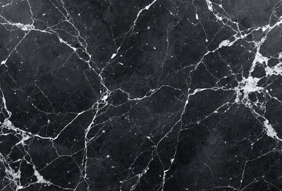 The primary subject of the image is a black and white marble tile. The setting is a black background, which contrasts with the marble tile. The visual style is a close-up of the marble tile, showcasing its texture and pattern. The colors and mood of the image are predominantly black and white, giving it a classic and elegant appearance.