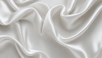 The primary subject of the image is a white sheet of fabric, which is the main object, scene, or focus of the image. The setting is a white background, which provides a clean and minimalistic environment. The visual style is a close-up of the fabric, showcasing its texture and details. The colors and mood of the image are predominantly white, giving it a clean, serene, and elegant appearance.