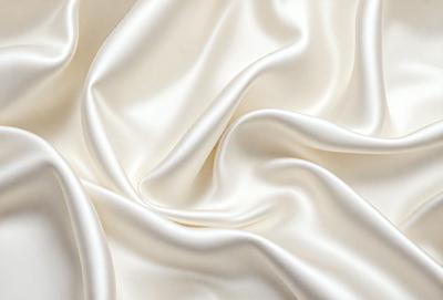 The primary subject of the image is a white fabric, possibly a sheet or a curtain, with a smooth and shiny texture. The setting is a white background, which provides a clean and minimalist appearance. The visual style is a close-up of the fabric, showcasing its details and texture. The colors and mood of the image are predominantly white, giving it a clean, elegant, and serene atmosphere.