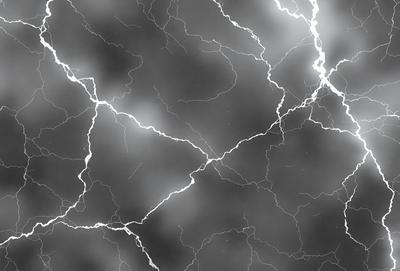 The primary subject of the image is a cloudy sky with lightning streaks. The setting is a dark, cloudy background, and the visual style is a black and white photo. The dominant colors are black, white, and grey, creating a moody atmosphere.