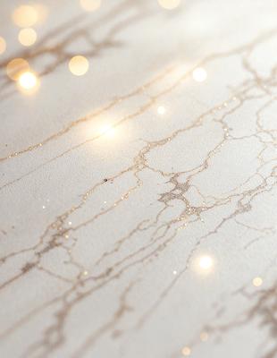 The primary subject of the image is a marble countertop with a glossy finish. The setting is a room with a white background, and the visual style is a photo. The countertop has a gold and white color scheme, giving it a luxurious and elegant appearance.