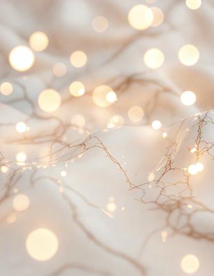 The primary subject of the image is a white sheet with a pattern of lights on it. The sheet appears to be a piece of fabric with a light pattern, possibly a lace or a net-like texture. The setting is a room with a bed, and the visual style is a close-up of the sheet with the lights. The colors and mood of the image are predominantly white, with the lights adding a touch of warmth and brightness to the scene.