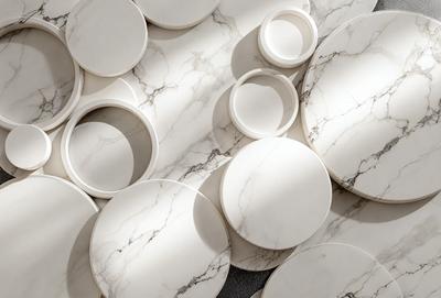 The primary subject of the image is a collection of white plates arranged on a marble surface. The setting is a room with a marble floor, and the visual style is a photo. The dominant colors are white and grey, creating a clean and elegant atmosphere.