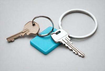 The primary subject of the image is a set of keys, which are the main objects in the scene. The keys are placed on a white surface, which serves as the background. The visual style of the image is a photo, capturing the details of the keys and their surroundings. The colors in the image are predominantly white and blue, giving the scene a clean and organized appearance.