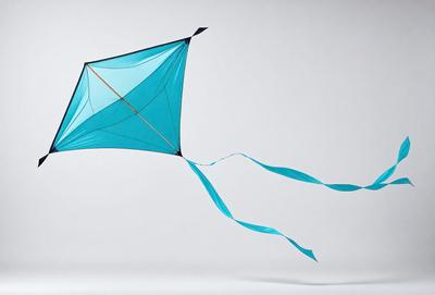 The primary subject of the image is a blue kite flying in the air. The kite is shaped like a butterfly and has long tails. The setting is a white background, which provides a clean and uncluttered environment for the kite to be the main focus. The visual style of the image is a photo, capturing the kite in its natural flight. The colors and mood of the image are predominantly blue, creating a sense of calmness and freedom.