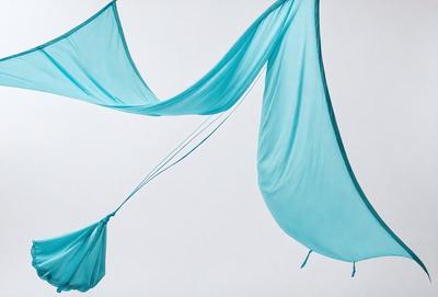 The primary subject of the image is a blue sheet hanging in the air. The sheet is long and appears to be made of fabric. The setting is a white background, which provides a clean and minimalistic appearance. The visual style is a close-up of the blue sheet, showcasing its texture and color. The overall atmosphere is calm and serene, with the blue sheet creating a sense of tranquility.