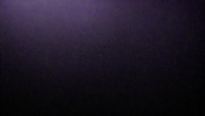 The image is a black and white photo of a purple background. The primary subject is a large, empty space with no visible objects or details. The setting is a dark, purple background that contrasts with the black and white photo. The visual style is a simple, monochromatic composition. The colors and mood of the image are predominantly dark and moody, with the purple background creating a sense of depth and mystery.