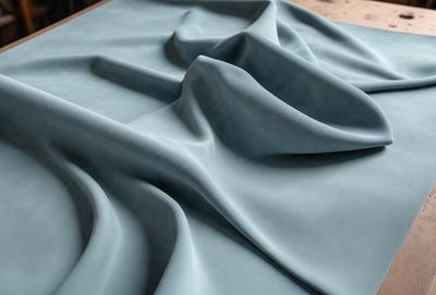 The primary subject of the image is a blue fabric, possibly a piece of cloth or a blanket, with a wrinkled texture. The setting is a table, and the visual style appears to be a close-up of the fabric. The colors and mood of the image are predominantly blue, giving it a calm and serene atmosphere.