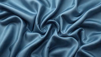 The primary subject of the image is a blue fabric, which appears to be a piece of silk. The setting is a blue background, which complements the blue fabric. The visual style is a close-up of the fabric, showcasing its texture and details. The colors and mood of the image are predominantly blue, creating a calm and serene atmosphere.