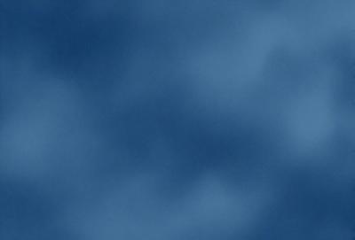 The primary subject of the image is a cloudy blue sky. The setting is a vast expanse of the sky, with no visible land or other objects. The visual style is a natural, outdoor scene. The colors and mood are predominantly blue, with a slightly overcast atmosphere.