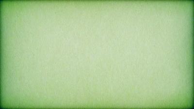 The primary subject of the image is a large, green, textured surface. The setting is a plain, empty room with a green background. The visual style is a close-up of the green surface, which appears to be a piece of fabric or a wallpaper with a textured pattern. The colors and mood of the image are predominantly green, creating a calm and serene atmosphere.