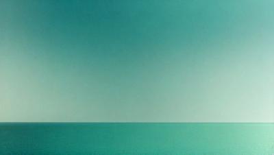 The primary subject of the image is the vast ocean, with a clear blue sky serving as the backdrop. The visual style of the image is a photo, capturing the beauty of the ocean and the sky. The colors and mood of the image are predominantly blue, creating a serene and calming atmosphere.