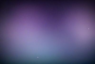 The primary subject of the image is a purple sky with a few stars visible. The setting is a vast, open space with no visible landmarks or objects. The visual style is a combination of a photo and digital art, creating a unique and artistic representation of the sky. The colors and mood of the image are predominantly purple and serene, evoking a sense of calmness and tranquility.