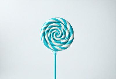The primary subject of the image is a blue and white striped lollypop. The lollypop is placed on a blue background, which creates a contrasting and visually appealing scene. The lollypop is the main focus of the image, and its vibrant colors and unique design make it stand out against the blue background.