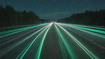 The primary subject of the image is a highway with a green glow. The setting is a nighttime cityscape, and the visual style is a photo. The dominant colors are green and blue, creating a serene and calming atmosphere.