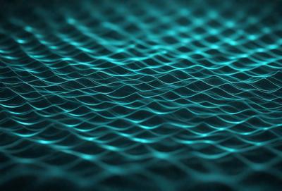 The primary subject of the image is a blue and green patterned surface, which appears to be a textured or wavy material. The setting is a dark background, which contrasts with the vibrant colors of the pattern. The visual style of the image is a close-up of the pattern, showcasing its intricate details. The colors and mood of the image are lively and energetic, with the blue and green hues creating a sense of movement and dynamism.