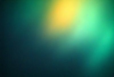 The primary subject of the image is a green background with a yellow spot. The setting appears to be a dark room, and the visual style is a close-up of the green and yellow spot. The colors and mood of the image are predominantly green and yellow, creating a warm and inviting atmosphere.