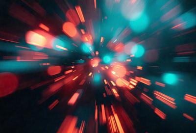 The primary subject of the image is a brightly colored, swirling, and blurry pattern. The setting is a dark background, which contrasts with the vibrant colors of the pattern. The visual style appears to be a combination of a photo and digital art, creating a dynamic and eye-catching effect. The dominant colors are red, green, and blue, giving the image a lively and energetic atmosphere.