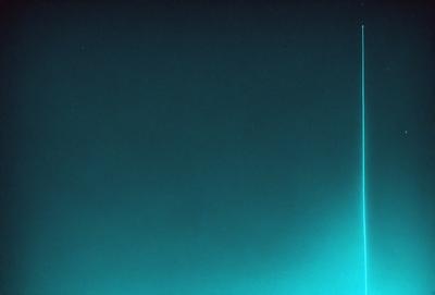 The primary subject of the image is a blue background with a green line or streak running through it. The setting appears to be a dark, possibly nighttime, environment. The visual style of the image is a combination of a photo and a digital art or illustration, as it features a blue and green color scheme with a distinctive line or streak. The overall atmosphere of the image is somewhat mysterious and intriguing, as the green line or streak adds an element of interest and curiosity to the otherwise dark and empty background.