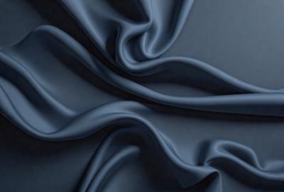 The primary subject of the image is a blue fabric, which is the main object, scene, or focus of the image. The setting or background is a dark blue surface, which provides a contrasting backdrop for the fabric. The visual style of the image is a close-up of the blue fabric, showcasing its texture and details. The colors and mood of the image are predominantly blue, creating a calm and serene atmosphere.