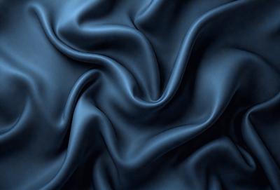 The primary subject of the image is a blue fabric, which appears to be a piece of silk. The setting is a dark background, which contrasts with the blue fabric. The visual style is a close-up of the fabric, showcasing its texture and pattern. The colors and mood of the image are predominantly blue, creating a calm and serene atmosphere.