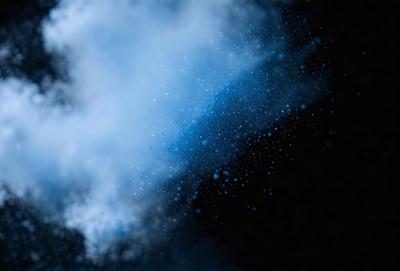 The primary subject of the image is a blue and white cloud. The setting is a dark background, which contrasts with the cloud. The visual style is a photo, capturing the cloud's movement and texture. The dominant colors are blue and white, creating a serene and calming atmosphere.