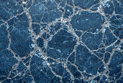 The primary subject of the image is a blue and white marbled wall. The setting is a room with a blue and white marbled wall as the main focus. The visual style is a close-up of the marbled wall, showcasing its intricate patterns. The colors and mood of the image are predominantly blue and white, creating a calm and serene atmosphere.
