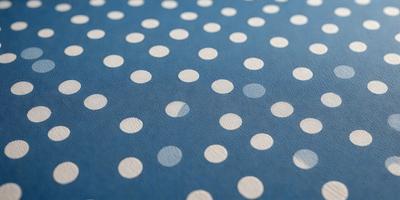The primary subject of the image is a blue fabric with white polka dots. The setting is a table, and the visual style is a patterned fabric. The colors and mood of the image are predominantly blue and white, creating a calm and soothing atmosphere.