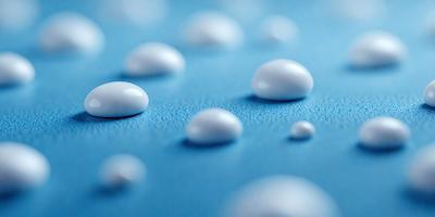 The primary subject of the image is a blue surface with white bubbles or droplets scattered across it. The setting appears to be a blue background, possibly a table or a wall. The visual style of the image is a close-up of the blue surface with the white bubbles, creating a sense of depth and texture. The colors and mood of the image are predominantly blue and white, giving it a calm and serene atmosphere.