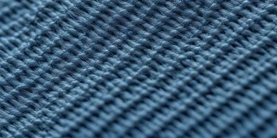 The primary subject of the image is a close-up of a blue fabric with a knitted texture. The setting is a dark background, which contrasts with the blue fabric. The visual style is a close-up of the fabric, showcasing its intricate knitted pattern. The colors and mood of the image are predominantly blue, creating a calm and serene atmosphere.